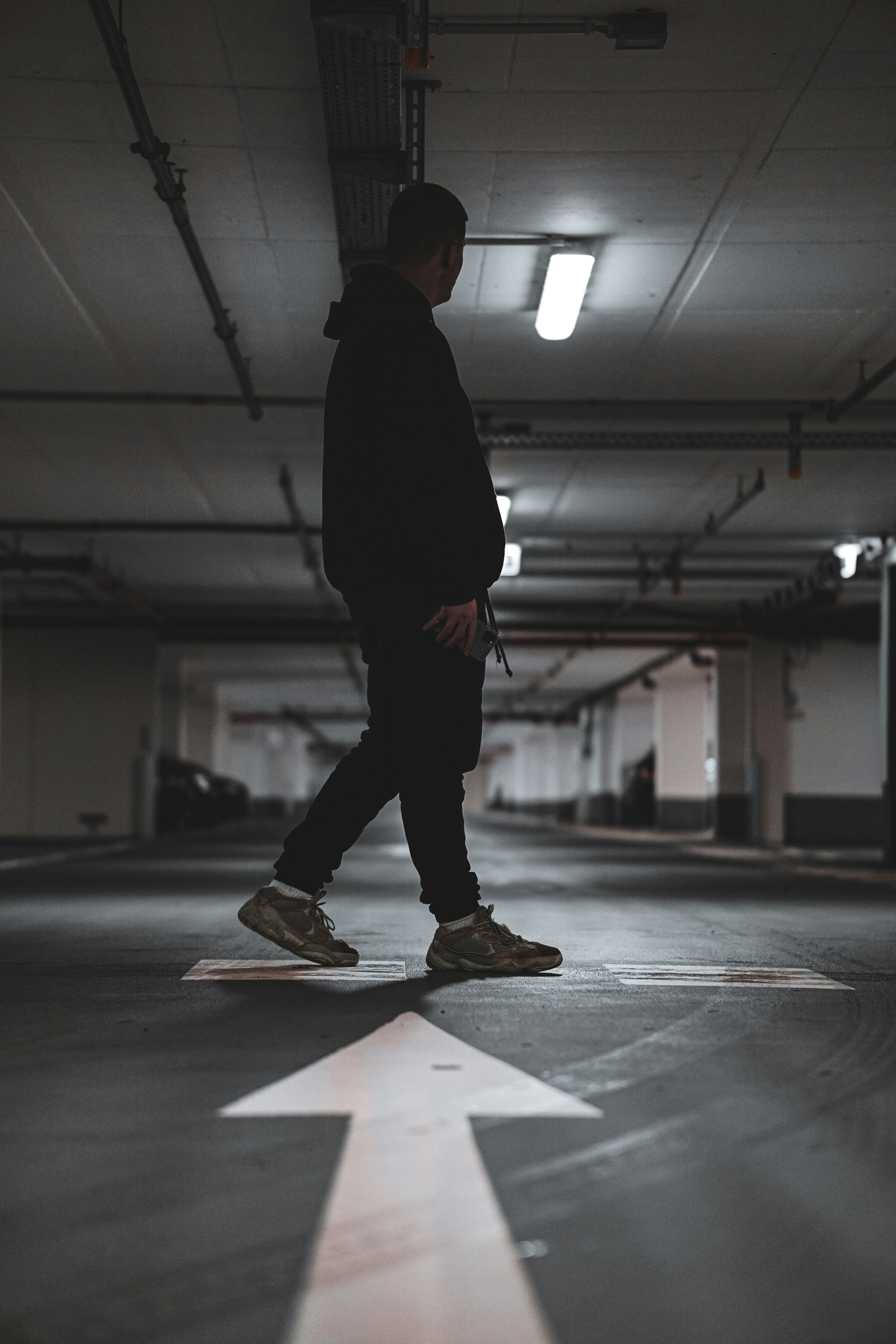 man in black jacket and pants walking on gray pavement